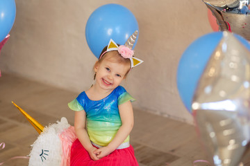 happy cute girl 3-4 years in the rim of a unicorn dancing in a bright outfit, birthday, holiday, balloons