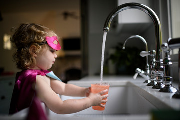 Girl filling water in drinking glass at home