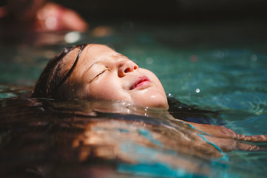 Close up of girl with eyes closed swimming in pool