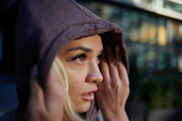 Close up of thoughtful woman wearing hood outdoors during sunrise