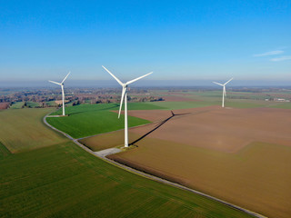 Aerial view of wind turbines and agricultural fields on a beautiful blue winter day - Energy...