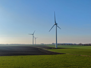 Aerial view of wind turbines and agricultural fields on a beautiful blue winter day - Energy Production with clean and Renewable Energy - aerial shot, analog image style