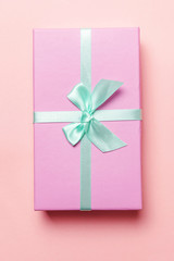 Christmas New Year birthday valentine celebration present romantic concept. Small gift box wrapped pink paper isolated on pink pastel colorful trendy background. Flat lay top view copy space