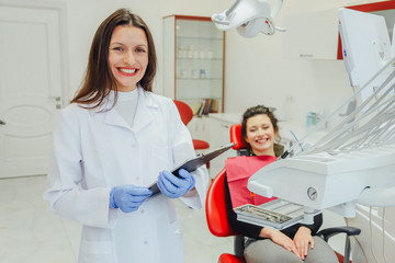 A dentist, showing a young woman with a patient's X-ray tooth in the dentist's office. Discussion of issues. Cropped snapshot of a professional dentist.