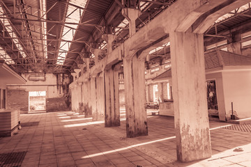 Naklejka na ściany i meble The ruins of an old abandoned factory. Perspective of abandoned warehouse from the inside with translucent roof and concrete structure.