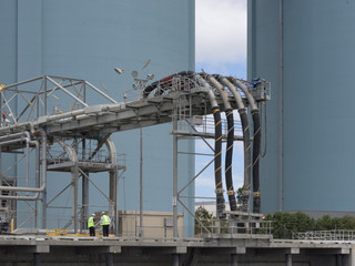 Two men in hard hats and yellow safety vests outside an industrial facility