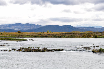 Road highway 32 in Iceland on golden circle with autumn rocky landscape view on cloudy day and river water mountains