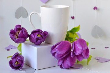 White coffee mug mockup with flowers tulips. Empty mug layout for design promotion. Marchendise Mock Up mug. Template for the inscription on the cup. Fresh spring composition. Paper hearts background.