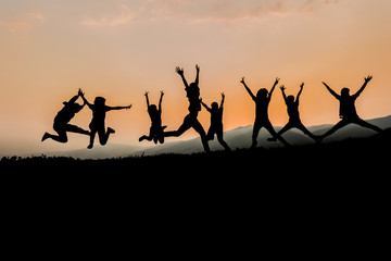 silhouettes; Group of happy people playing at summer sunset in nature