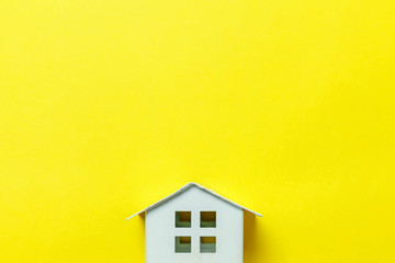 Simply design with miniature white toy house isolated on yellow colourful trendy modern fashion...