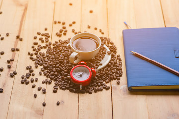 White cup full of coffee beans on Roasted Coffee Beans and wood background, top view