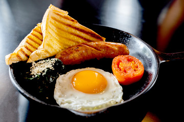 English breakfast: fried egg, bacon, sausage and toast in pan.