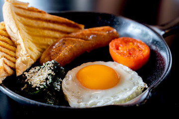 English breakfast: fried egg, bacon, sausage and toast in pan.