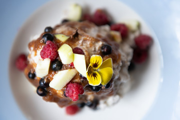 Flat top view of homemade raw vegan ice cream salad and fresh fruit berries from garden on plate with date syrup topping and yellow pansy edible flower