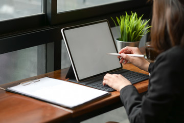 Businesswoman in cafe working on digital tablet with pencil