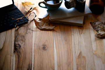 Coffee with keyboard tablet, autumn leaves on wooden table and copy space