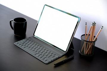 Tablet with smart keyboard case with blank screen on dark wood table