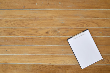 Clipboard with white sheet on wooden background