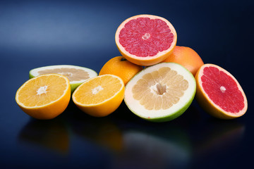 cut pieces of different citrus fruits on dark background