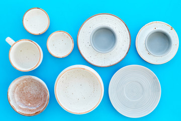 Kitchen concept. Crockery kit. Empty ceramic plates and mugs on blue background top view