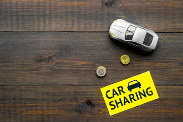 Carsharing concept, carsharing sign. Economical, chip trip. Toy car near coins on dark wooden...
