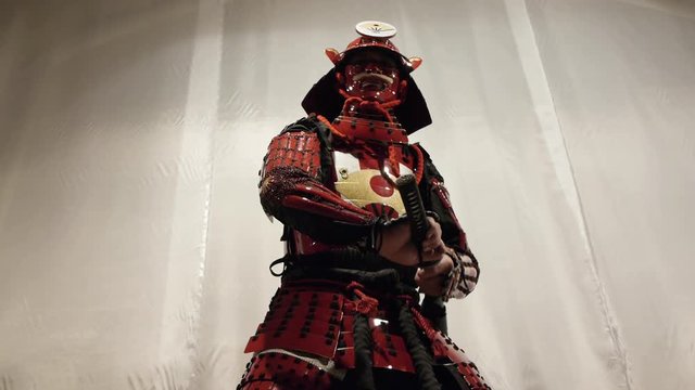 samurai in red helmet doing exercises with a katana sword