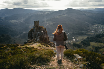 Fototapeta premium young woman watching medieval tower ruins built on a rock