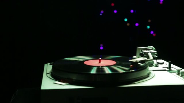 The player plays music on a vinyl record in the light of disco