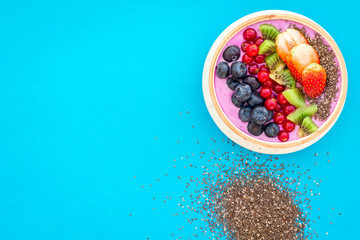 Superfoods. Acai smoothie bowl with fresh fruits, berries, chia seeds on blue background top view space for text