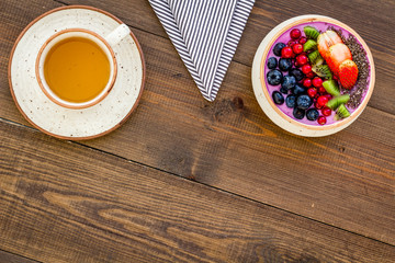 Healthy vegetarian breakfast. Acai smoothie bowl with fresh fruits, berries, chia seeds on dark wooden background top view copy space