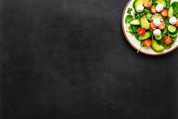 Healthy lunch. Fresh vegetable salad on black background top view space for text
