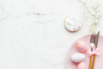 Easter table setting. Tableware and painted eggs on white background top view space for text