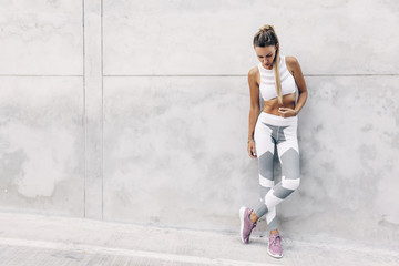 Fitness sport model in fashion sportswear posing over gray wall