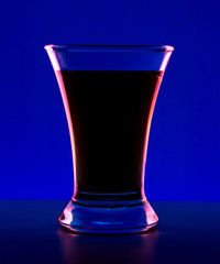 Glass or stemware with alcohol wine,whiskey,gin,beer,rum,vodka,Scotch,cognac,liquor,brandy,absinthe or cocktail on blue background. A glass on the bar in a cafe, restaurant, nightclub or disco.