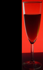 Glass or stemware with alcohol wine,whiskey,gin,beer,rum,vodka,Scotch,cognac,liquor,brandy,absinthe or cocktail on red background. A glass on the bar in a cafe, restaurant, nightclub or disco.