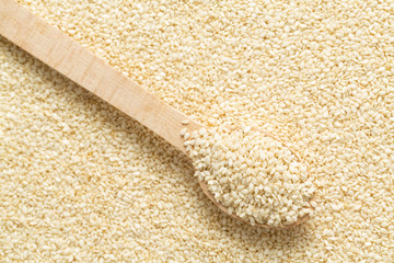 Sesame seeds in a wooden spoon top view. Sesame seeds background
