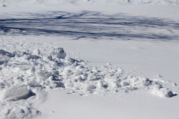 Clumps of snow from a snow blower creates a fluffy abstract texture on a snowy ground