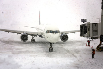 Commercial Jet Airplane Pulling up to Gate in Blizzard Snowstorm