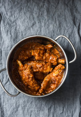 Braised pork ribs in tomato sauce in pan on grey background, top view