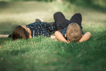 Children relax in nature. Brothers lie on the grass and watch the clouds