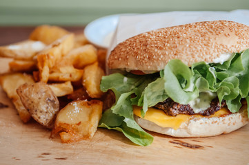 Beef hamburger, fried potato chunks close up shot