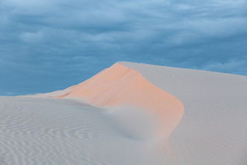 Fototapeta na wymiar Beautiful white sand dune under cloudy sunset skies. Anna Bay, New South Wales, Australia