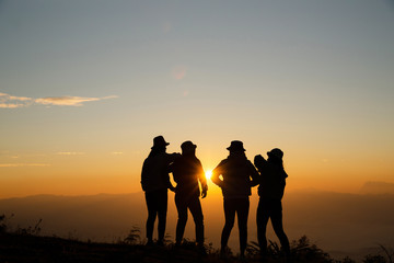 Silhouette of young woman are standing on top of the mountain relaxing with sunrise by nature at sunrise, Life style, Group of happy at sunrise or sunset, First morning light