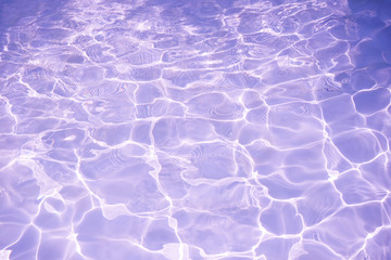 Rippled pattern of clean water in a purple swimming pool for background