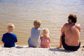 Family of Father and his Children Sitting on Beach Looking at Water