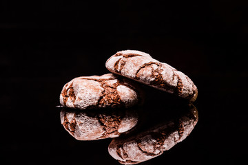 chocolate cookies with icing sugar are laid on a black background