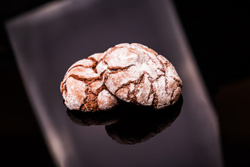 chocolate cookies with icing sugar are laid on a black background