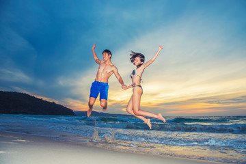 Happiness young couple jumping with happy on the beach at sunset. Vacation and freedom travel. Love, wedding and valentine concept.