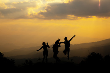 Fototapeta na wymiar Group of happy people jumping in the mountain at sunset, concept about having fun on the hill, silhouette