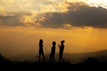 Silhouette, group of happy girl playing on hill, sunset, summertime